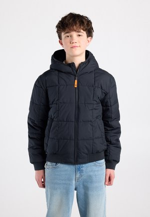 Padded black jacket with a hood, zip front, orange accent, and ribbed cuffs. Features a quilted design for insulation. Worn with light blue jeans.