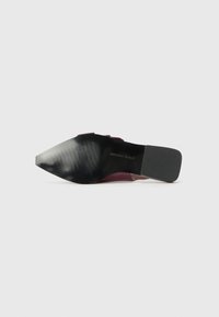 Pointed-toe shoe with a black, textured sole, burgundy upper, and a sleek design. Features a shiny finish and a low slant heel.