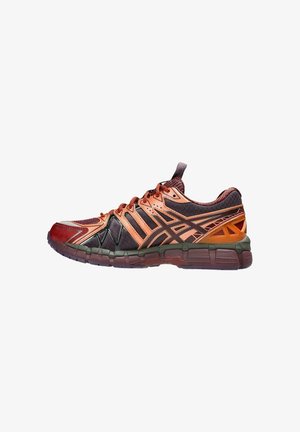 Zapatillas deportivas en materiales rojos, naranjas y verde oscuro; parte superior texturizada con malla; diseño estratificado distintivo; suela flexible con patrón de agarre.