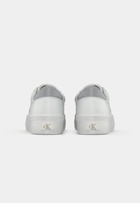 Witte sneakers van glad synthetisch materiaal, ronde vorm, grijze accenten aan de achterkant en een rechthoekige metalen logo-detail.