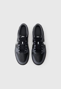 Nike tenisice s gornjištem od crne kože i sive mrežice, okrugli vrh, vezanje sprijeda, s bijelim swoosh logom i perforiranim detaljima.