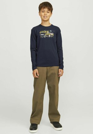 Marineblauwe T-shirt met lange mouwen, voorzien van een grafische logo in geel en wit. Gecombineerd met olijfgroene wijde broek en zwarte sneakers.