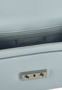Interno di una borsa in pelle azzurro struttura con una tasca centrale con zip e una chiusura metallica con due borchie decorative.