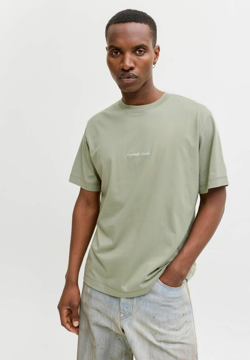 Hele roheline puuvillane t-särk ümarate kraega ja lühikeste varrukatega. Ees on diskreetne broderi tekst. Kandmiseks sobivad kulunud denim lühikesed püksid.