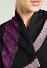 Zwart gebreide sjaal met golvende patronen in paars en lichtroze en een gestructureerde afwerking. Close-up weergave die de stof en het kleurcontrast benadrukt.