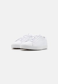 Vita sneakers med en slät syntetisk ovandel, rund tådesign och platta snören, med en strukturerad gummisula för bra grepp.