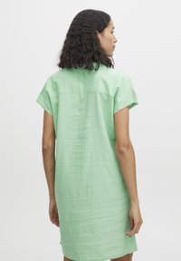 Vestido de manga corta en color verde menta, confeccionado en tela ligera. Presenta un ajuste simple y relajado, con un yugo en la parte posterior y un dobladillo recto.