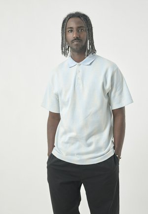 Light blue short-sleeve polo shirt with a subtle striped pattern, featuring a collar and three-button placket, paired with black pants.