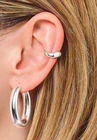 Orecchini a cerchio in argento con una finitura lucida, di forma circolare, abbinati a un piccolo cuffia per l'orecchio curva in argento.