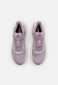 Zapatillas deportivas de color púrpura claro con parte superior de malla, punta redonda y cordones planos. Con logotipo en la lengüeta y en el lateral, y suela acolchada.