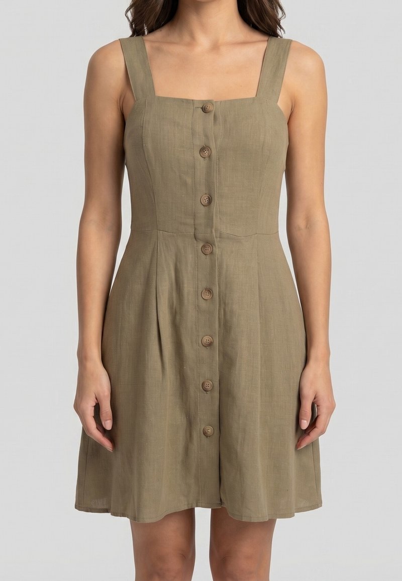Femme portant une robe kaki sans manches à boutons sur le devant, avec un col carré et une jupe évasée sur fond uni.