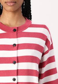 Rood met witte gestreepte cardigan met een ronde halslijn, voorzien van zwarte knopen aan de voorkant en een zachte, textuur-achtige stof.
