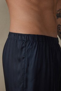 Shorts rayés bleu marine en tissu léger avec une taille élastique, présentant une texture lisse et une coupe ajustée.