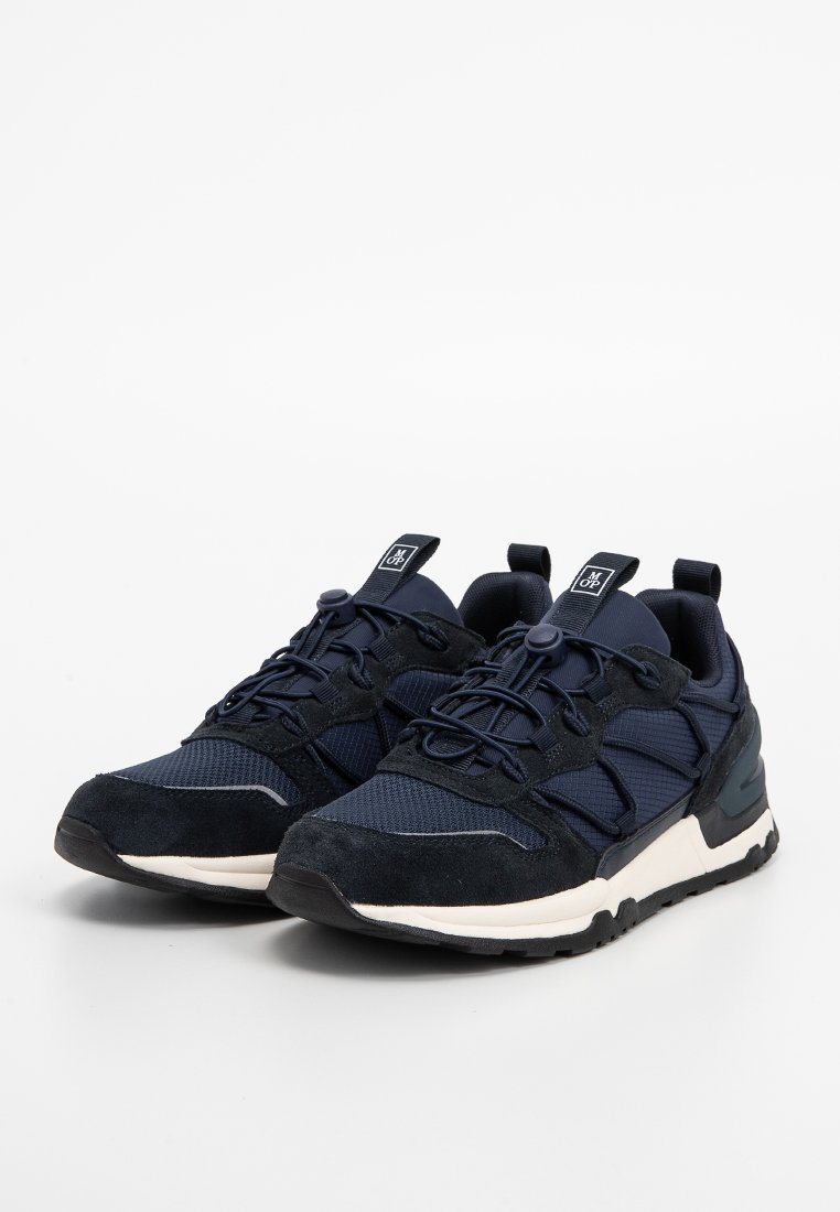 Para granatowo-czarnych butów sportowych z białymi podeszwami środkowymi i regulowanymi elastycznymi sznurowadłami na białym tle.