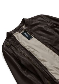 Giacca in pelle marrone con una superficie esterna texturizzata, dotata di hardware in ottone, chiusura con zip e fodera beige chiaro.