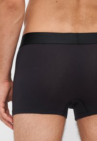 Sorte boxertruser laget av mykt materiale, med en glatt elastisk midjebånd og en tettsittende passform, med flat sømdesign.