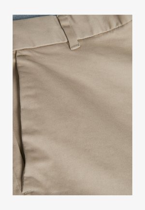 Tissu en coton khaki avec une texture lisse, comportant une ceinture plate et un détail de poche cousu sur le côté gauche.