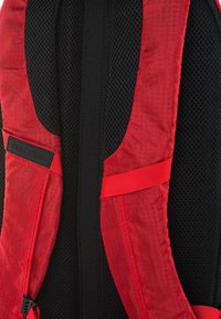 Mochila roja y negra con correas texturizadas rojas, panel trasero de malla y una etiqueta con el logo "SKECHERS" en la correa del hombro.