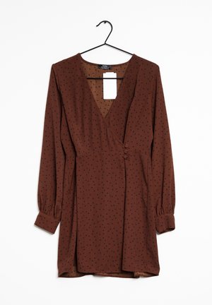 Brown long-sleeve wrap dress with small black polka dots, buttons at the waist, hanging on a black hanger with a white tag.