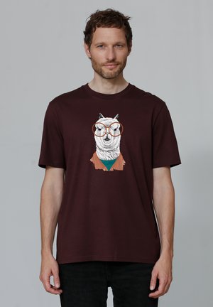 Bordeaux katoenen t-shirt met een afbeelding van een uil met een bril, gekleed in een bruine jas over een turquoise shirt, met korte mouwen en een relaxte pasvorm.