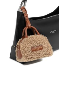 Borsa a spalla in pelle nera con accessori in argento, dotata di una piccola borsa fuzzy beige attaccata, con una toppa con logo e chiusura a zip.