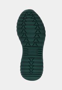 Semelle extérieure en caoutchouc vert avec un design texturé affichant des motifs triangulaires et des rayures surélevées, marqué du logo "GUESS".