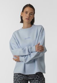 Jasnoniebieska bluza z ribbed crew neck i długimi rękawami. Z przodu subtelny napis "OH APRIL" w odrobinę ciemniejszym odcieniu.
