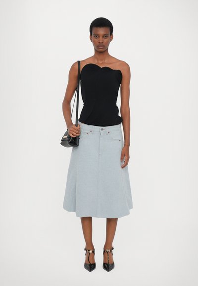 Black one-shoulder top, fitted design. Light blue denim A-line skirt, knee-length, with front buttons. Black pointed heels and small bag.