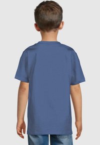 Mėlynas medvilninis T-shirt su trumpomis rankovėmis, apvaliu kaklu ir lygia nugara, dėvimas vaiko. Kasdienis kirpimas su lygia tekstūra.