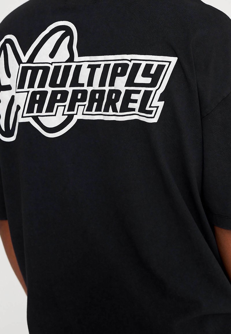 Černé bavlněné tričko s velkou bílou grafikou nápisu "MULTIPLY APPAREL" a designem motýla na zadní straně.