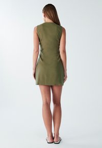 Abito senza maniche verde oliva con silhouette aderente, texture liscia e orlo corto. Design minimalista senza motivi visibili.
