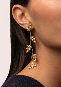 Pendientes en forma de hoja de oro con un acabado texturizado, que presentan un diseño retorcido que sigue la curva de la oreja.