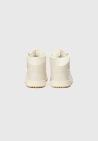 Baskets montantes en cuir blanc cassé avec col rembourré, détails cousus et semelle en caoutchouc beige. Logo embossé sur le talon.