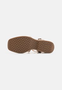 Sole di sandalo marrone chiaro con un motivo testurizzato di piccoli cuori. Realizzata in gomma, presenta una forma curvata e un leggero supporto dell'arco.