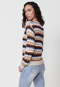 Multicolored knitted sweater featuring horizontal stripes of brown, cream, black, and blue, with a textured weave and ribbed hem.
