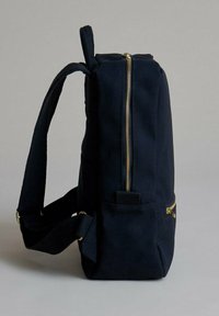 Zaino in tessuto blu navy con forma rettangolare, cerniera dorata e tasca laterale. Dotato di spallacci regolabili e maniglie robuste.