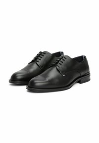 Zwarte leren dresschoenen met een gladde afwerking, ronde neus en gestructureerde bovenkant. Voorzien van een vetersluiting en een lage hak.