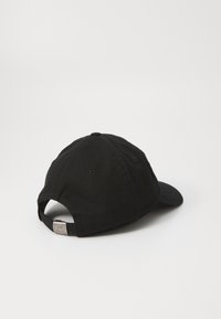 Gorra de béisbol de algodón negra con visera curva, correa ajustable en la parte posterior y un detalle de logo en la correa. Tejido texturizado.