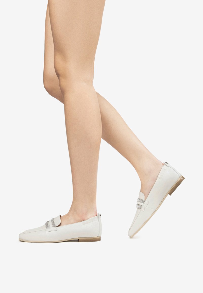 White loafers with textured fabric, decorative strap, and a low tan heel. Minimalistic design with a clean silhouette and easy slip-on style.