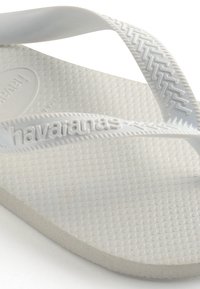Witte flip-flops met een gestructureerde rubberen zool en platte banden; voorzien van een debossed logo en een comfortabele voetbed met een patroon voor grip.