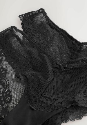 Černé spodní prádlo z kombinace krajky a síťoviny. Jeho design zdobí detailní květinové vzory s mašličkami a zvlněnými okraji.