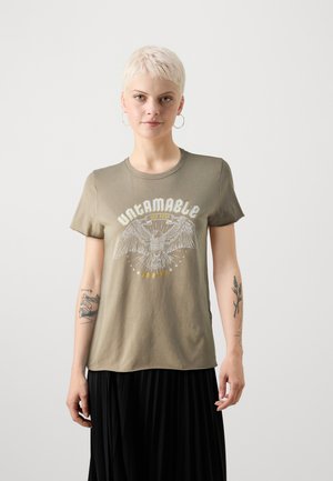 Olivgrünes Baumwoll-T-Shirt mit einem weißen Grafikdesign eines Adlers, dem Text "UNZÄHMBARE" und Sternen, runder Ausschnitt, kurze Ärmel.
