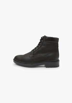 Črne usnjene gležnjarje z teksturiranim zaključkom, ki imajo kovinske luknjice in vezalke spredaj ter trdo gumijasto podplat.