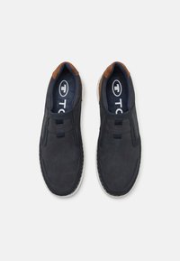 Marine slip-on sko med teksturert overdel, brune detaljer og hvit yttersåle. Har elastiske sidepaneler for enkel påkledning og en polstret såle.