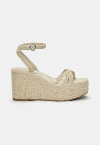 Sandales compensées en matériau naturel tressé, dotées d'une texture épaisse en corde, d'une bride à la cheville ajustable et d'une couleur beige neutre.
