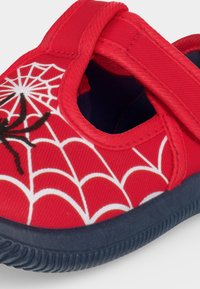 Chaussure enfant rouge avec semelle marine, ornée d'une toile d’araignée blanche et d’une araignée noire, avec fermeture à scratch.