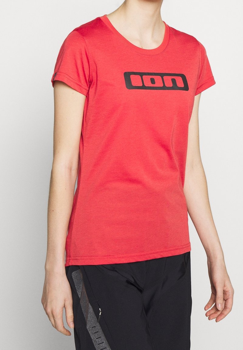 Red cotton t-shirt with a rounded neckline and short sleeves. Features a black logo across the chest. Smooth texture, casual design.