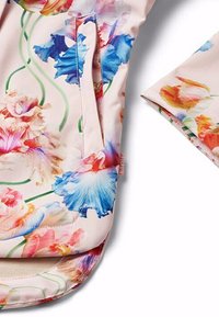 Blommönstrad tyg med rosa, blå och gula nyanser; har en ficka och en mjuk textur; inkluderar rundade kanter och en vikbar ärm.