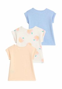 Tre T-shirts: en lys blå, en bleg orange, en cremefarvet med flerfarvede frugttryk. Korte ærmer, rundede halsudskæringer, blød tekstur.