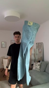 Svetlo modri jeans iz denima z zadnjim žepom z zapletenim vezenjem, rumenim obeskom na pasu in sproščenim krojem.